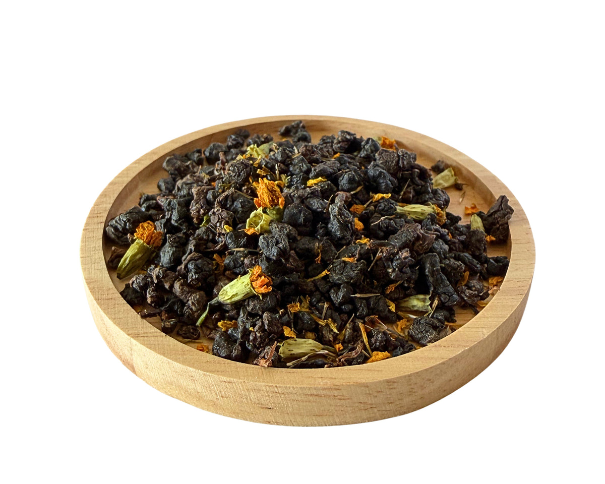 Harmony Tea rolled dry leaves and flowers on a wooden dish.